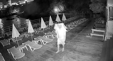 Elinde alkol şişesini alıp havluyla yüzünü gizleyip dans etti, onlarca plaj şemsiyesini denize attı